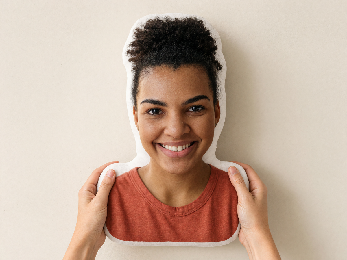 Die-cut face photo pillow of a smiling woman, held in two hands